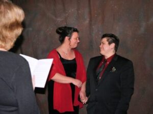 An officiant reading from a book as a couple holds hands during a wedding ceremony.