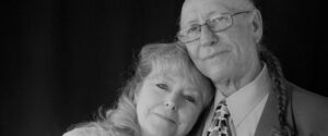 An older man with glasses and a woman leaning her head against his shoulder.
