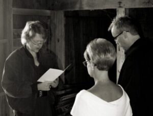 An officiant reads from a document during a wedding ceremony for a couple.