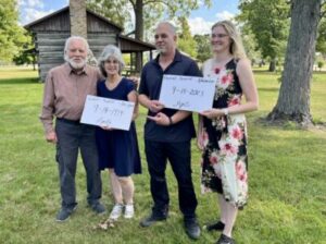 Four people standing outdoors holding signs with their names and the date 9-14-2023.