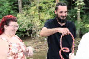 A man holds a multi-colored rope ring as a woman watches.