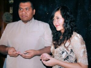 A man in a light-colored shirt and a woman in a lace top stand side-by-side.