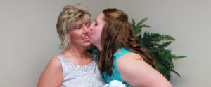 A young woman kisses her mother on the cheek.