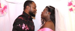 A bride in a veil and a groom in a floral shirt facing each other.