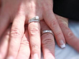 Two hands wearing wedding rings resting on top of each other.
