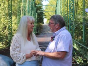 A man and woman standing on a green bridge holding hands.